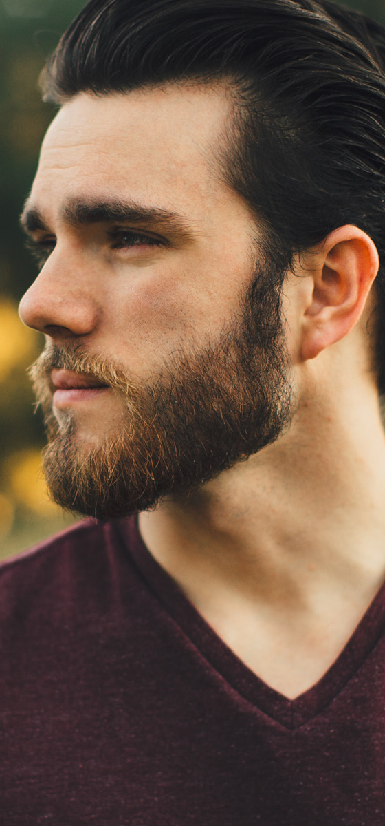 Immagine di un uomo, seduto in un prato, con una barba lunga